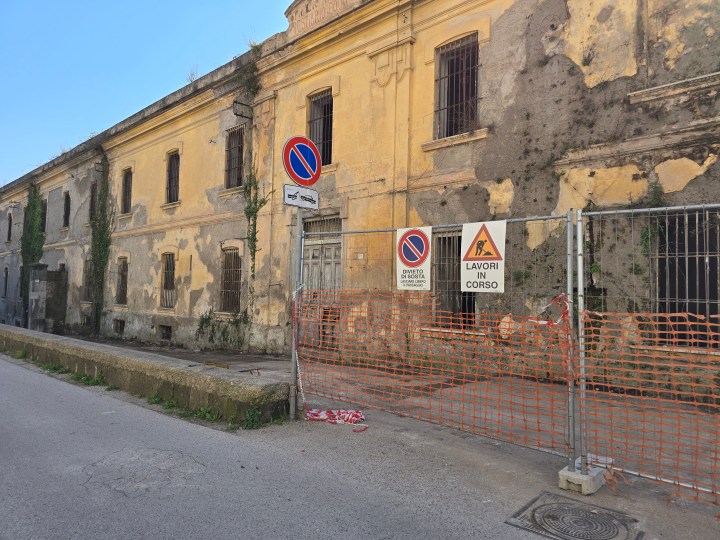 Edificio con distacco diffuso di intonaco su muratura in tufo e area transennata per rischio caduta materiali