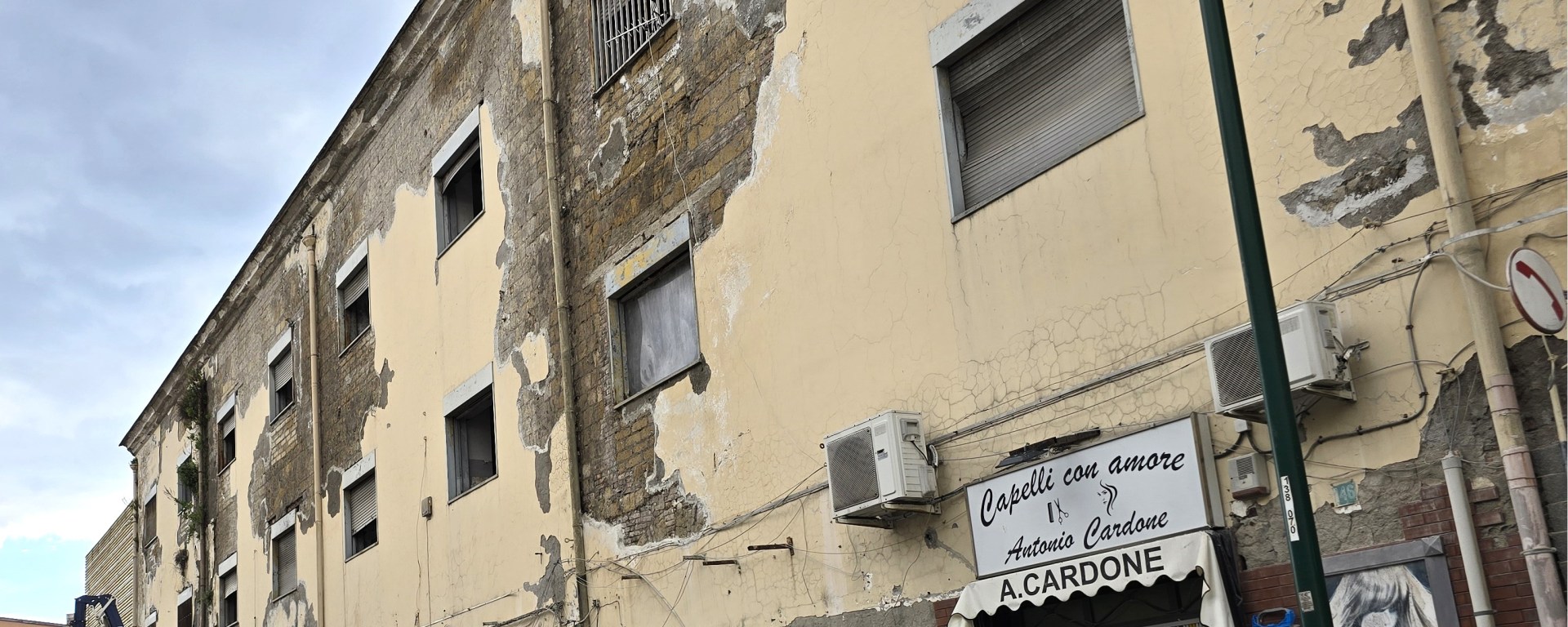 Distacco diffuso di intonaco cementizio su muratura in tufo con esposizione del supporto e degrado esteso della facciata