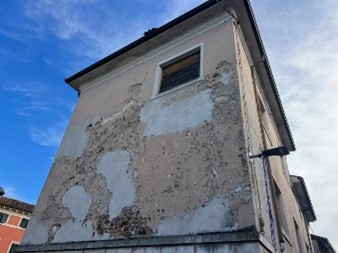 Facciata con rifacimenti disomogenei di intonaco su muratura in tufo e segni di interventi successivi nel tempo