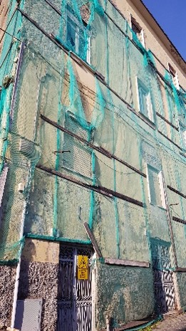 Facciata con reti e interventi sovrapposti su intonaco degradato a causa di rifacimenti non risolutivi