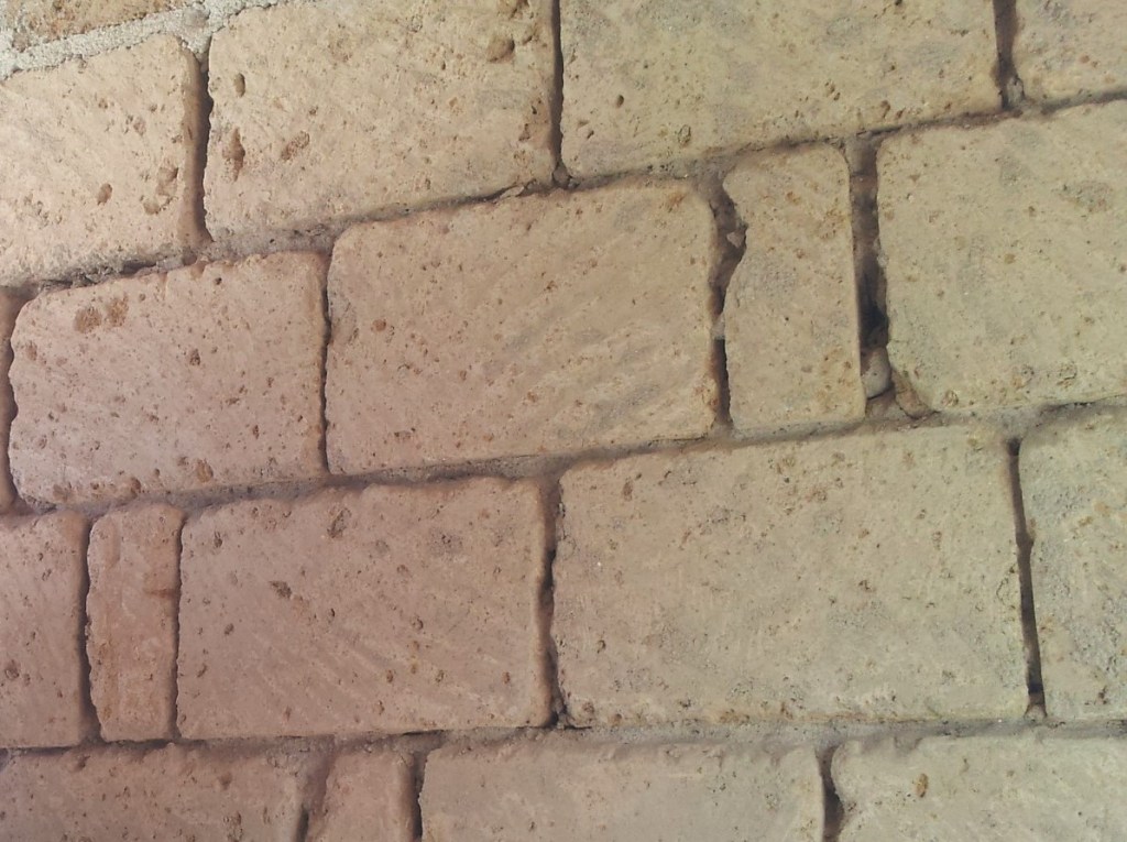 Muratura in tufo poroso con struttura irregolare e giunti aperti, materiale igroscopico