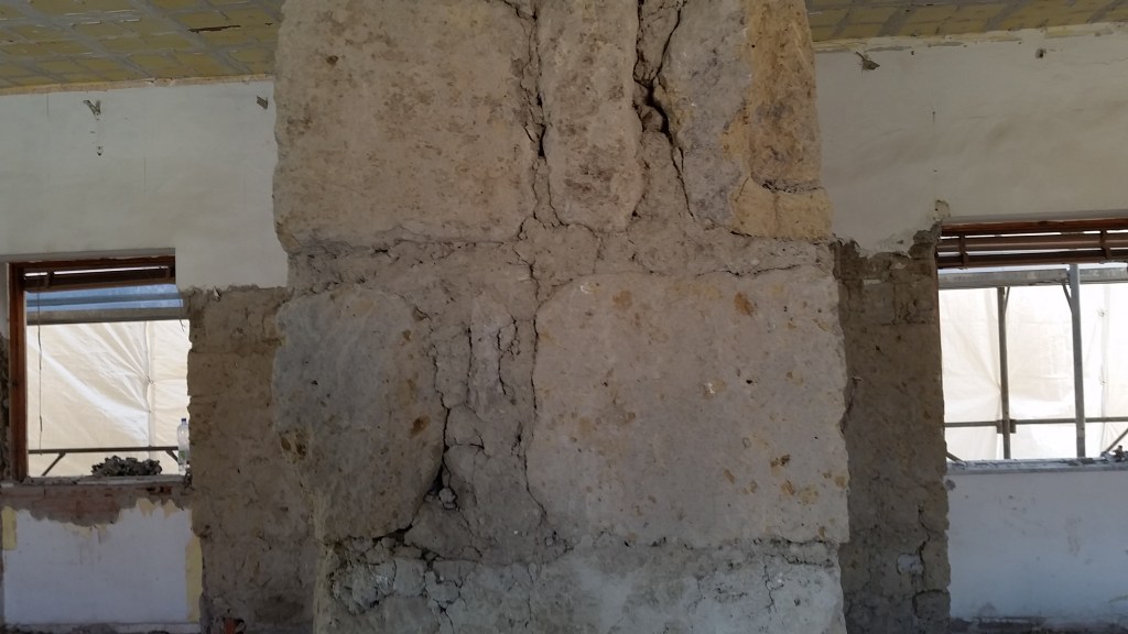 Muratura portante in conci di tufo con lesioni verticali e dissesti localizzati in edificio esistente